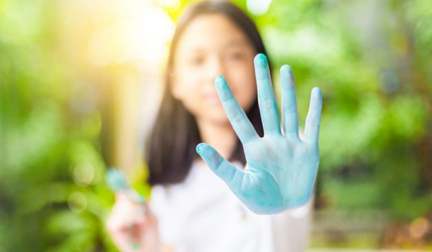 Funny child girl shows hands dirty with paint, Cheerful little c